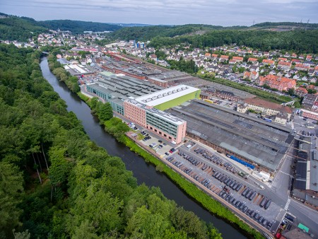 Aerial view of the Precision Steel plant (thyssenkrupp Hohenlimburg) by the river, surrounded by green spaces and residential areas. Aerial view of the Precision Steel plant (thyssenkrupp Hohenlimburg) by the river, surrounded by green spaces and residential areas.