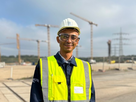 Belhassen Charfi in Schutzkleidung mit Helm und Warnweste auf einer Baustelle bei thyssenkrupp Steel.