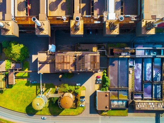 Aerial view of an industrial site belonging to thyssenkrupp Steel in Duisburg, showing production buildings, tanks, green spaces, and infrastructure.