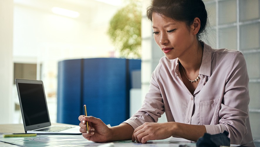 A person sitting at a desk in an office with a laptop and documents, working in a focused manner.