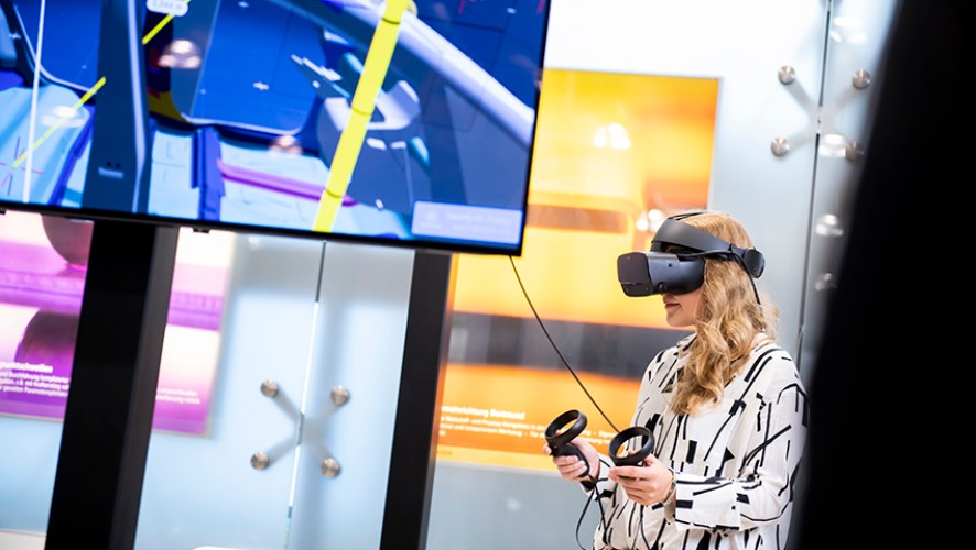 Eine Frau nutzt eine Virtual-Reality-Brille zur Interaktion mit einer technischen Simulation.