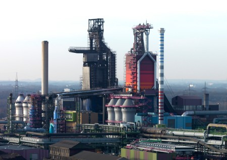 Moderne Technologie feiert 50. Jubiläum: Die Hochöfen bei thyssenkrupp Steel in Duisburg produzieren rund um die Uhr Roheisen. Damit dies weiter den hohen Umwelt- und Sicherheitsstandards entspricht, wurde nun der glockenlose Gichtverschluss, der im Innern für die gleichmäßige Verteilung des Materials sorgt, Im Hochofen 9 (li.) routinemäßig ausgetauscht. Vor 50 Jahren wurde dieses Bauteil zum ersten Mal in einem Hochofen eingesetzt.