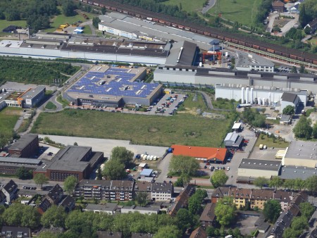 Aerial view of the thyssenkrupp Electrical Steel plant in Gelsenkirchen with industrial buildings, green spaces, and adjacent residential areas. Aerial view of the thyssenkrupp Electrical Steel plant in Gelsenkirchen with industrial buildings, green spaces, and adjacent residential areas.