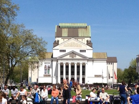 View of the Duisburg City Theater with classical architecture and a park area in the foreground.