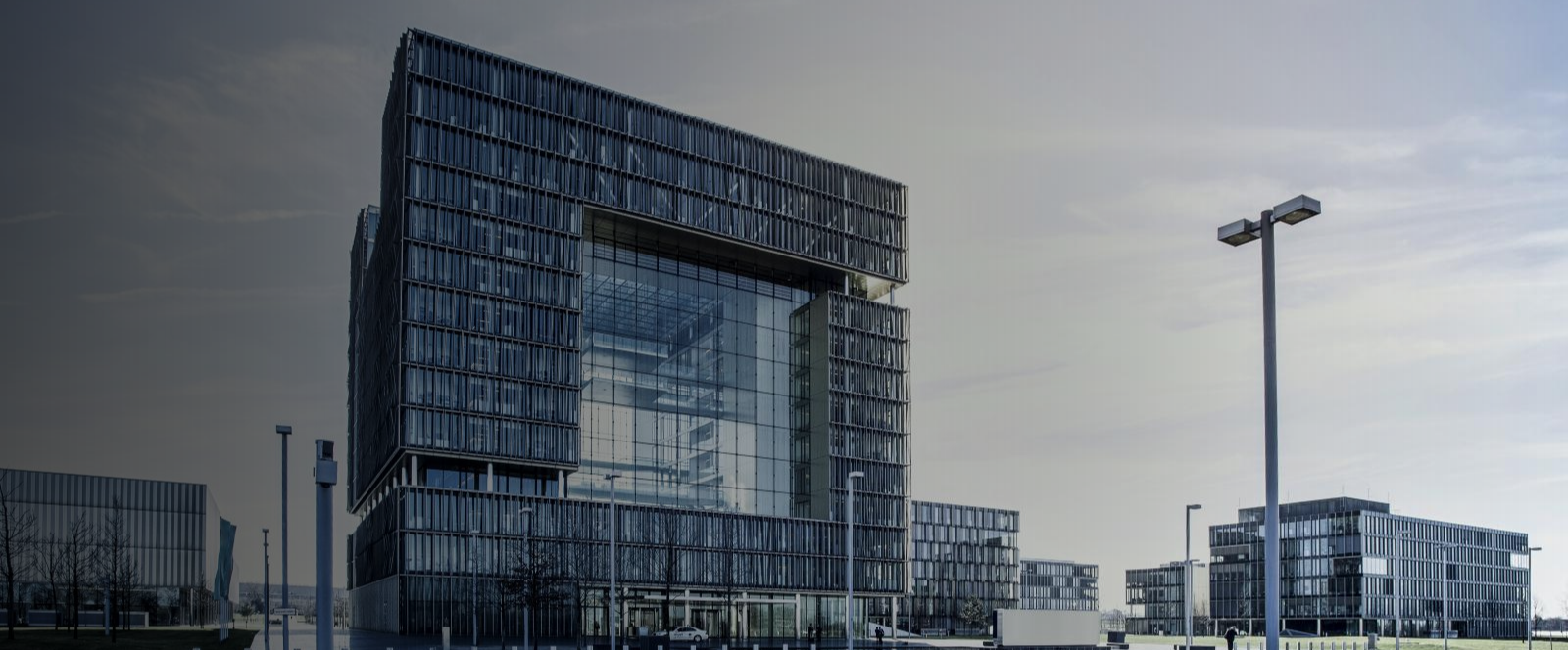 Das thyssenkrupp Quartier der AG in Essen mit zentralem Glasgebäude, umliegenden Bürogebäuden und gepflastertem Außenbereich bei klarem Himmel.