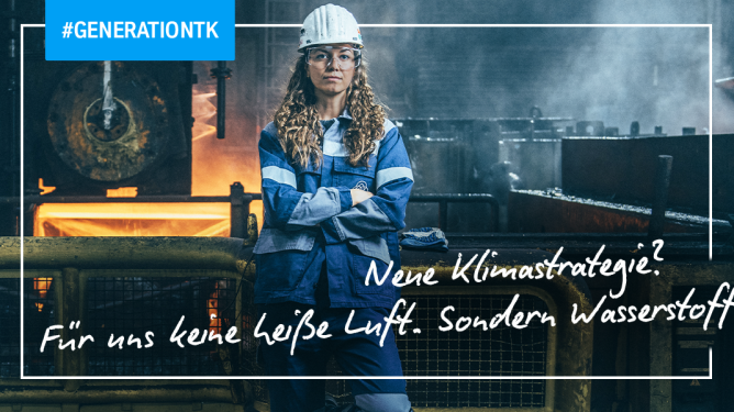 In einer großen Industriehalle steht eine Mitarbeiterin in blauer Arbeitskleidung und mit Schutzhelm vor einer Anlage mit glühendem Stahl. Geländer, Maschinen und Rohre umgeben den Arbeitsbereich.