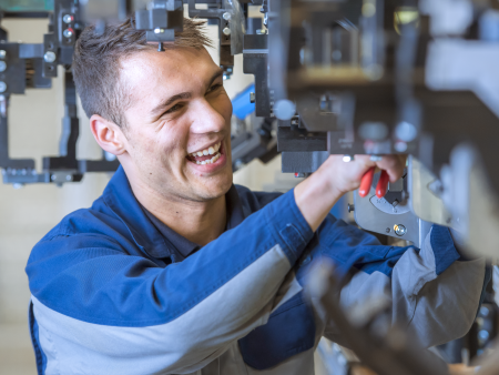 Trainee at thyssenkrupp Steel working on a machine with tools. Trainee at thyssenkrupp Steel working on a machine with tools.
