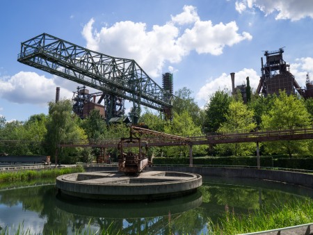 View of Landschaftspark Duisburg-Nord featuring a water basin, metal structure, and surrounding greenery.