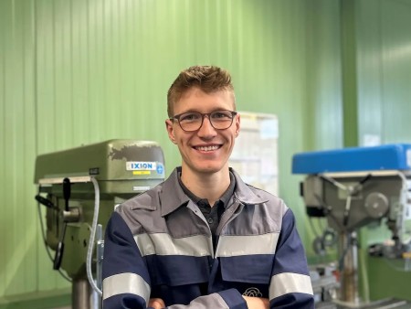 Elias Mayer wearing workwear with reflective stripes in front of machinery in an industrial setting at thyssenkrupp Steel. Elias Mayer wearing workwear with reflective stripes in front of machinery in an industrial setting at thyssenkrupp Steel.