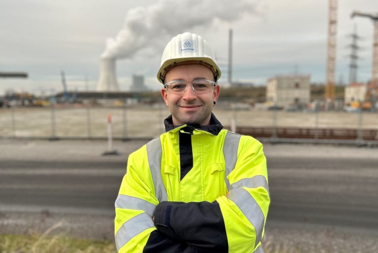 Nico Kruse wearing safety gear and a helmet in front of an industrial facility at thyssenkrupp Steel.