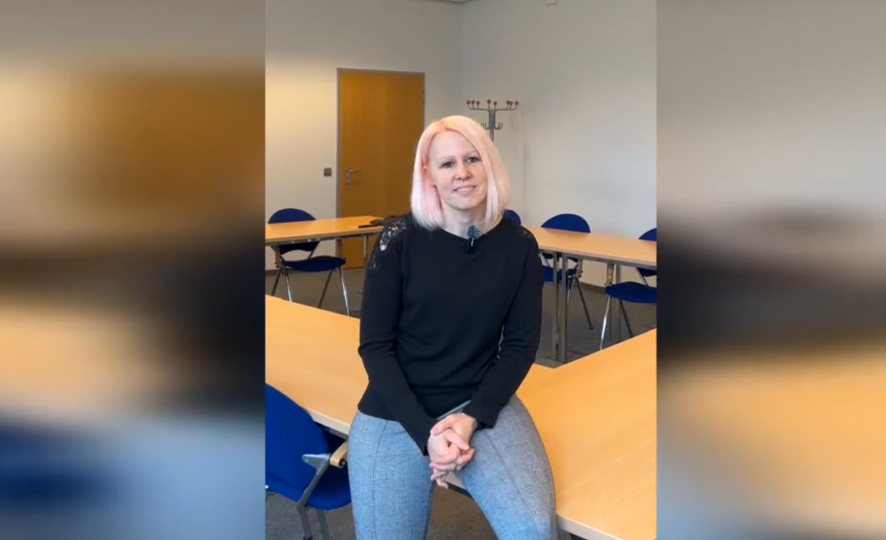 Nina Suchy is interviewed in a room with tables and chairs.